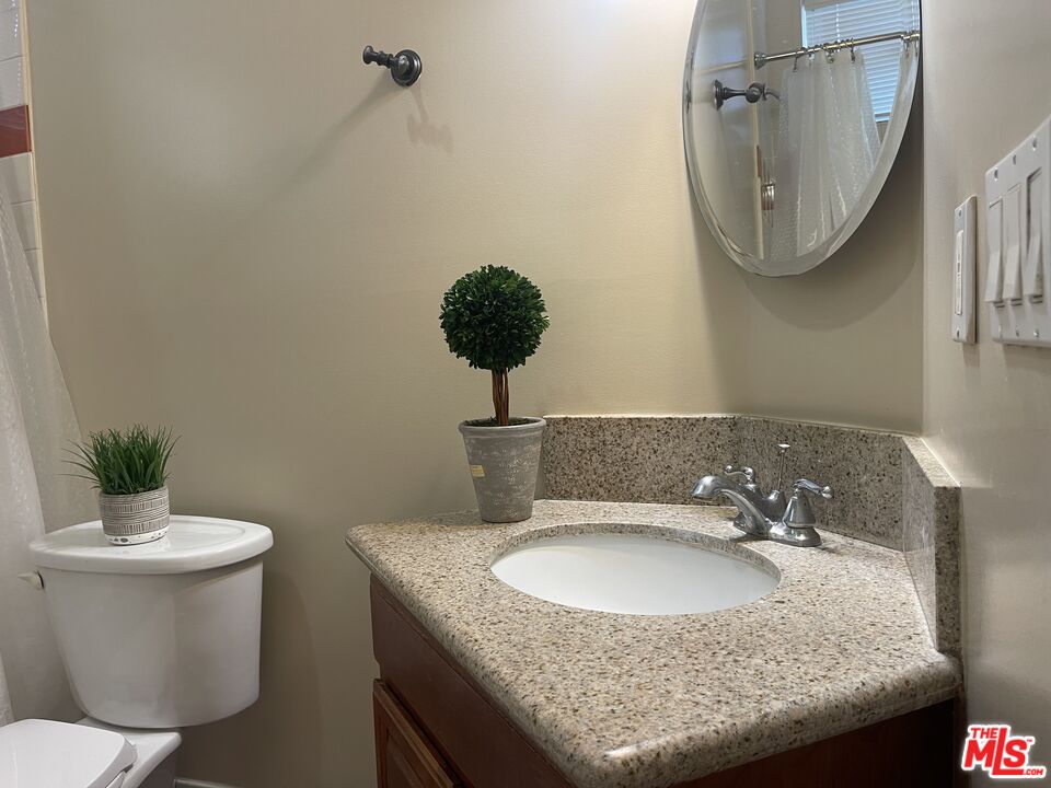 904 East Windsor Road, Unit 103 Glendale, CA 91205 - Photo 24 of 26 a bathroom with a granite countertop sink a toilet and a mirror