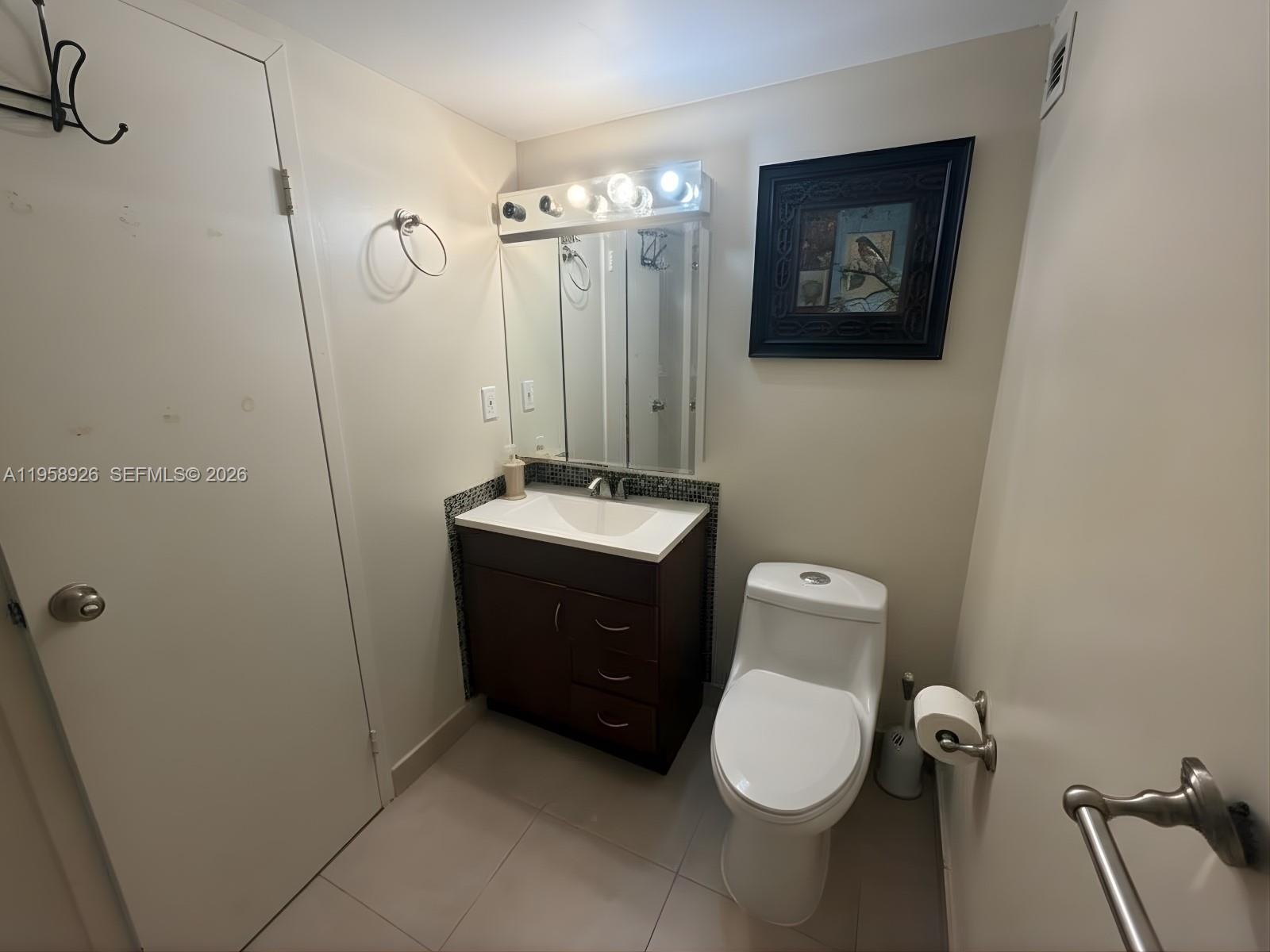 17021 North Bay Road, Unit 706 Sunny Isles Beach, FL 33160 - Photo 4 of 14 a bathroom with a toilet a sink and mirror