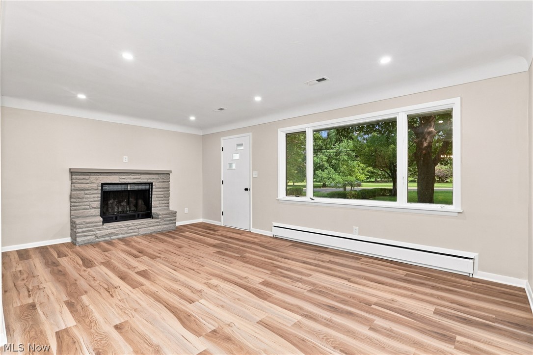 7524 Root Road North Ridgeville, OH 44039 - Photo 5 of 50 Stone-clad fireplace with hearth, wood-finish flooring, recessed ceiling lighting, and a large picture window