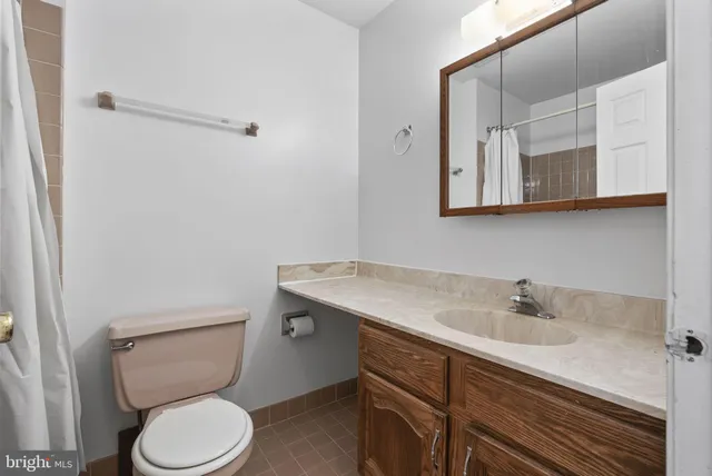 a bathroom with a granite countertop toilet sink and mirror