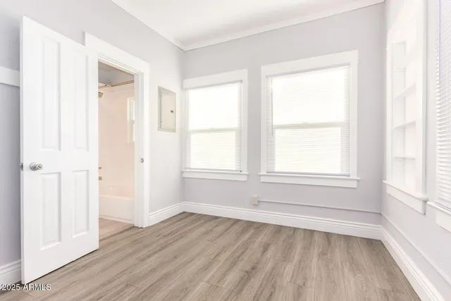 an empty room with wooden floor and windows