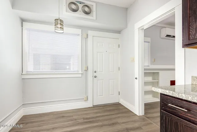 an empty room with wooden floor cabinet and windows