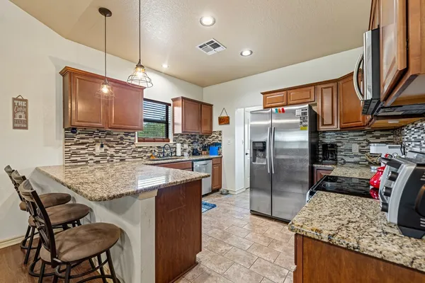 a kitchen with stainless steel appliances granite countertop a sink refrigerator and microwave