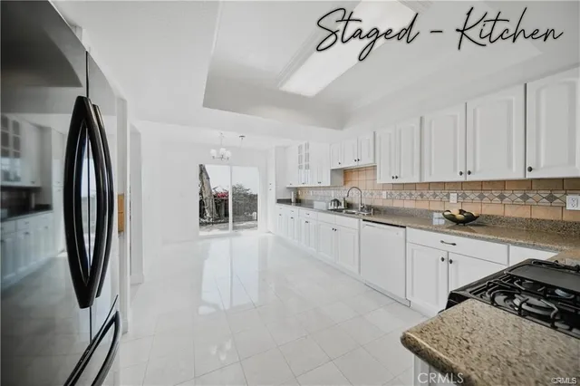 a kitchen with stainless steel appliances granite countertop a refrigerator a sink dishwasher a stove and white cabinets