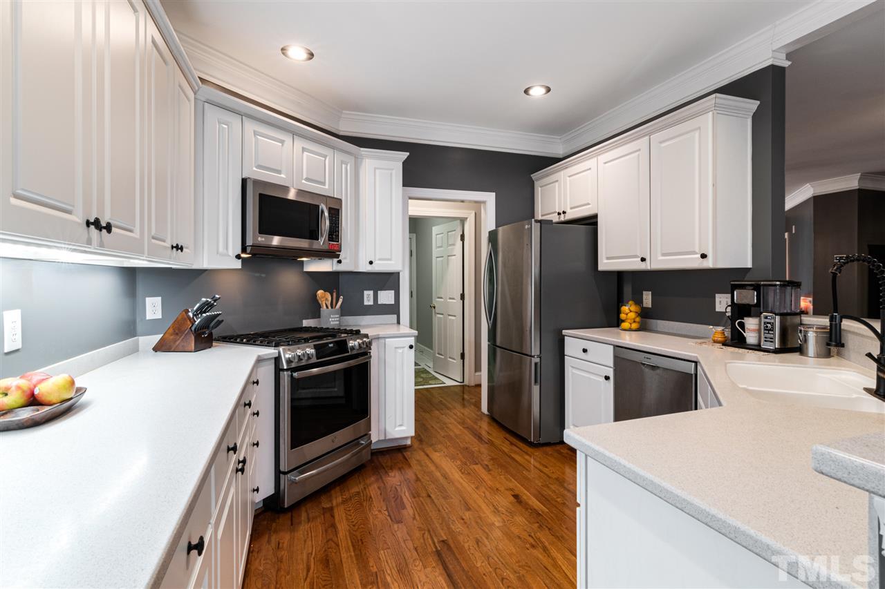 2408 Carruthers Court Raleigh, NC 27615 - Photo 8 of 30 a kitchen with granite countertop a refrigerator a stove top oven a sink and dishwasher with wooden floor