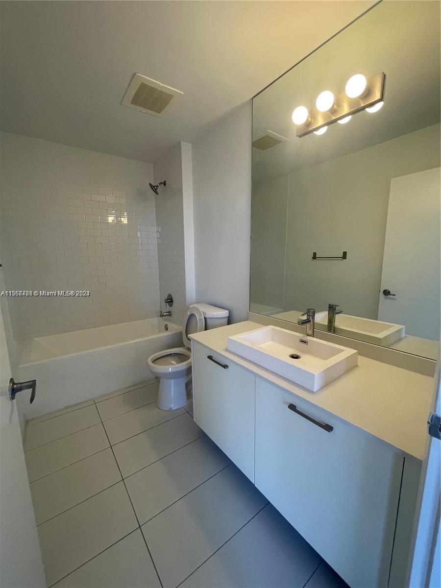 151 Southeast 1st Street, Unit 1505 Miami, FL 33131 - Photo 10 of 23 a bathroom with a granite countertop sink mirror and toilet