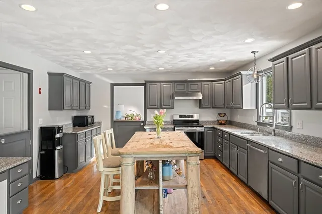 a kitchen with stainless steel appliances granite countertop a stove top oven a sink dishwasher a dining table and chairs