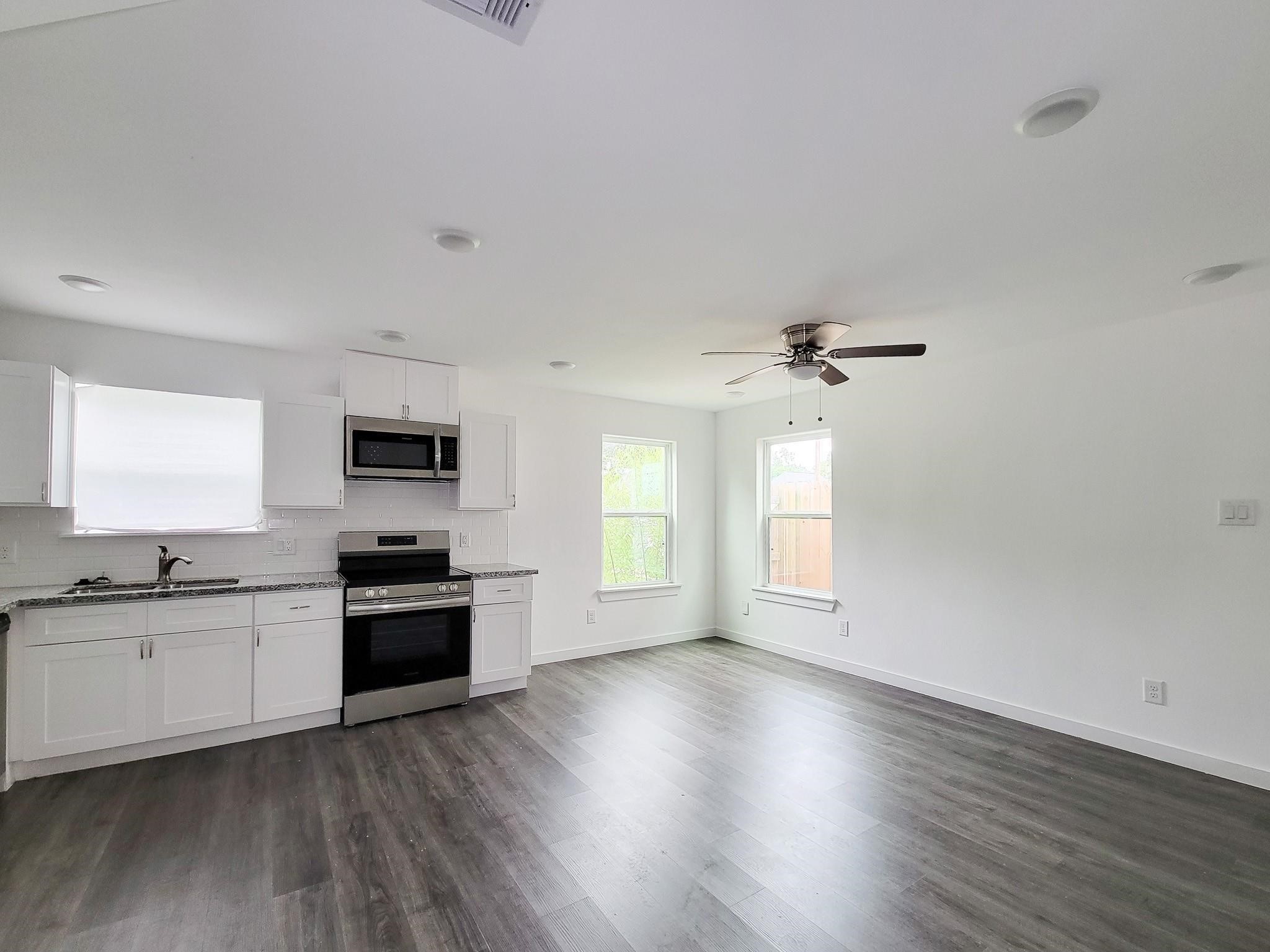 8122 Sterlingshire Street, Unit B Houston, TX 77078 - Photo 6 of 27 a kitchen with granite countertop a stove top oven a sink dishwasher and a refrigerator with wooden floor