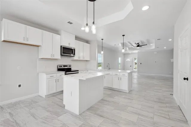 a large kitchen with stainless steel appliances kitchen island granite countertop a stove top oven a sink a counter top space and cabinets