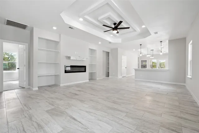a view of an empty room with a window and kitchen view