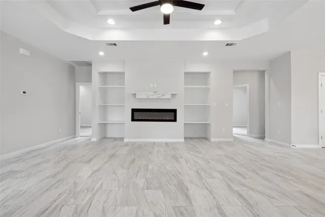 an empty room with wooden floor ceiling fan and windows