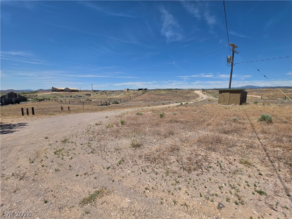 2930 Frehner Ranch Road Pioche, NV 89043 - Photo 19 of 39 Rolling landscape with a winding dirt road and distant structures, offering a tranquil setting.
