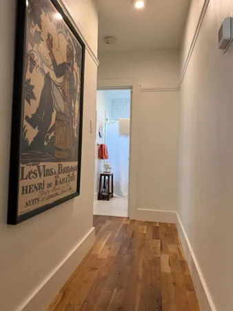 a view of a hallway with wooden floor and a bathroom