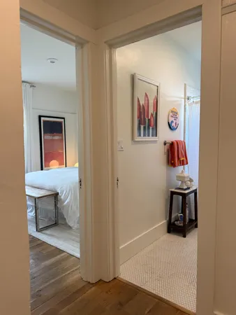 a view of a hallway to room with wooden floor and furniture
