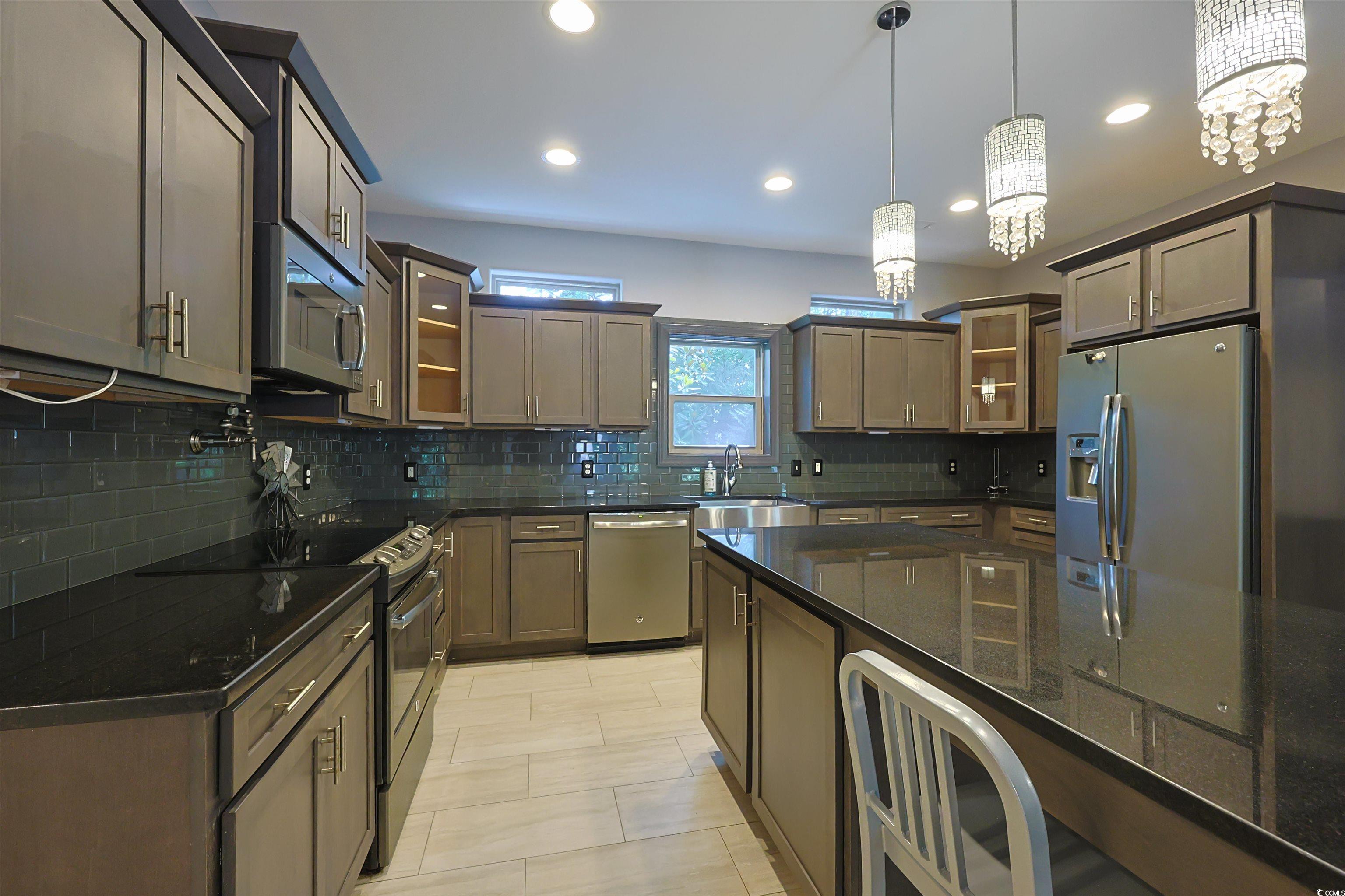 1065 Wigeon Drive Conway, SC 29526 - Photo 7 of 40 Kitchen with glass insert cabinets, appliances with stainless steel finishes, decorative backsplash, pendant lighting, and recessed lighting