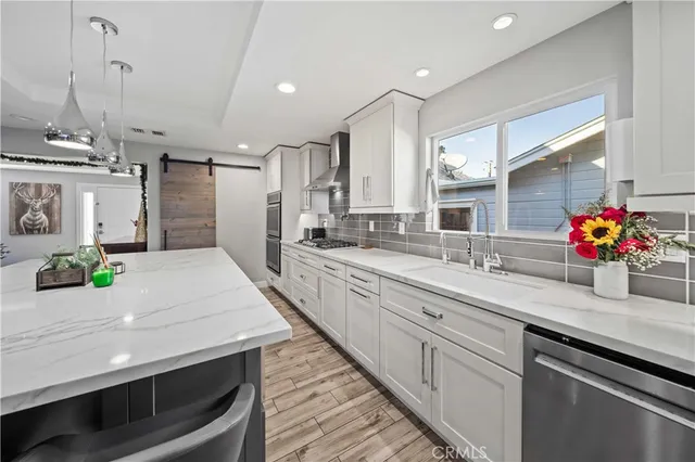 a kitchen with stainless steel appliances a stove a sink and white cabinets