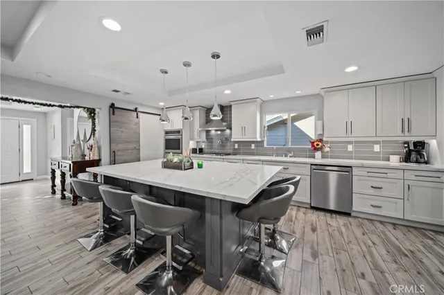 a kitchen with stainless steel appliances a dining table chairs refrigerator and sink