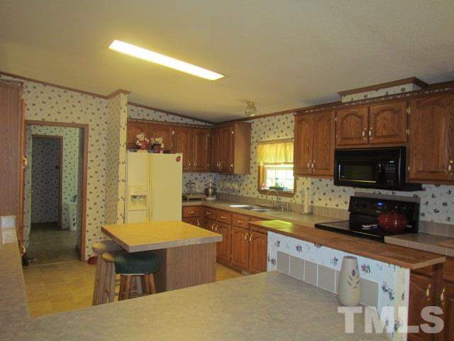 109 Medlin Road Rougemont, NC 27572 - Photo 10 of 19 a kitchen with stainless steel appliances granite countertop a sink a stove top oven a counter space and cabinets