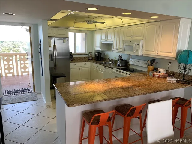 a kitchen with granite countertop white cabinets and white appliances