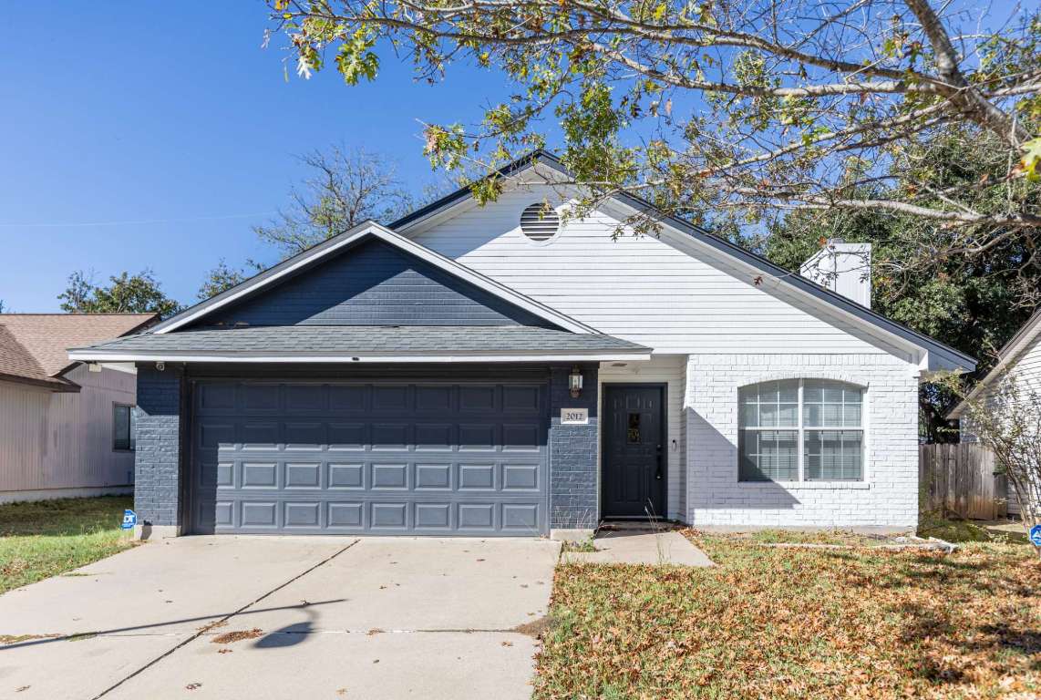 Single story home featuring brick siding, concrete driveway, a chimney, and a garage
