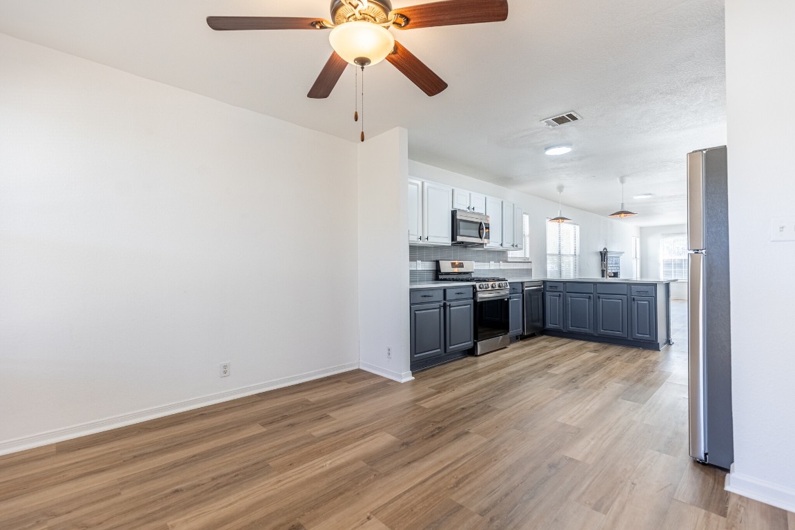 2012 Balsam Way Round Rock, TX 78665 - Photo 14 of 30 Kitchen with appliances with stainless steel finishes, light countertops, a peninsula, a ceiling fan, and white cabinetry