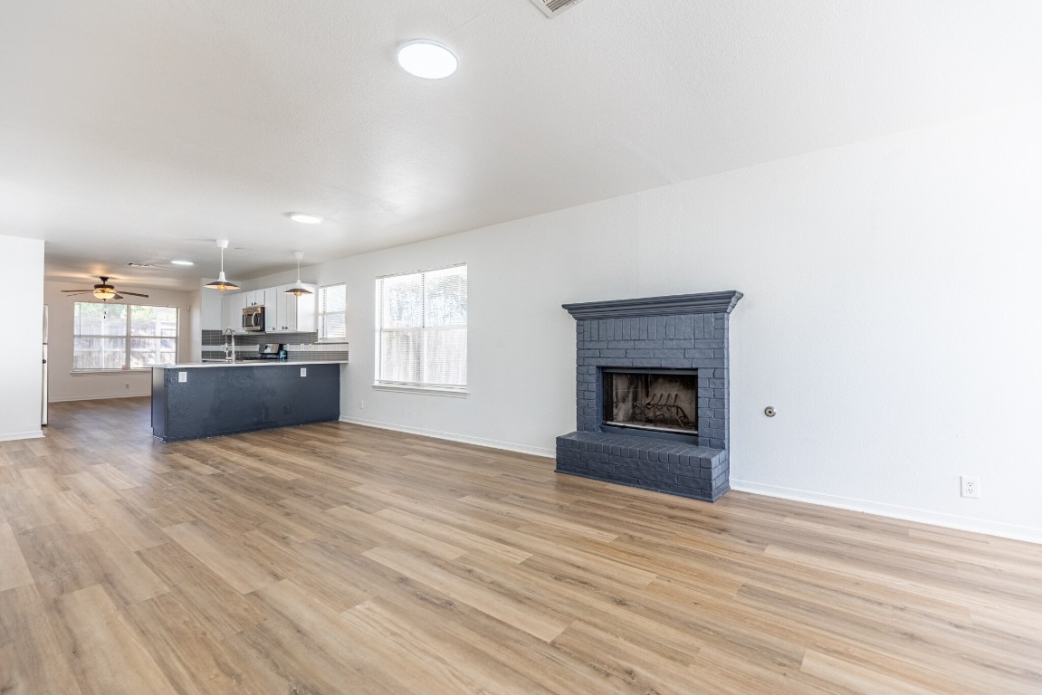 2012 Balsam Way Round Rock, TX 78665 - Photo 4 of 30 Unfurnished living room with a brick fireplace, ceiling fan, and light wood-type flooring