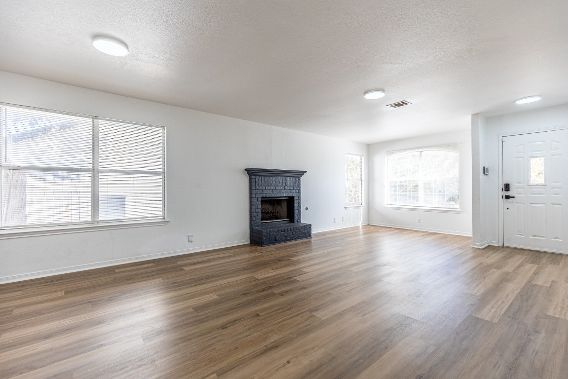 2012 Balsam Way Round Rock, TX 78665 - Photo 5 of 30 Unfurnished living room with a brick fireplace, wood finished floors, and a textured ceiling