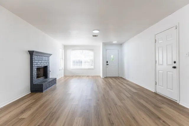 an empty room with wooden floor and fireplace