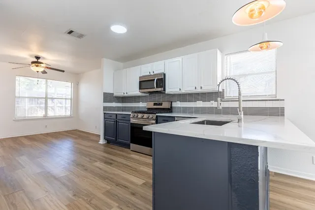 a kitchen with granite countertop a stove a sink and a microwave
