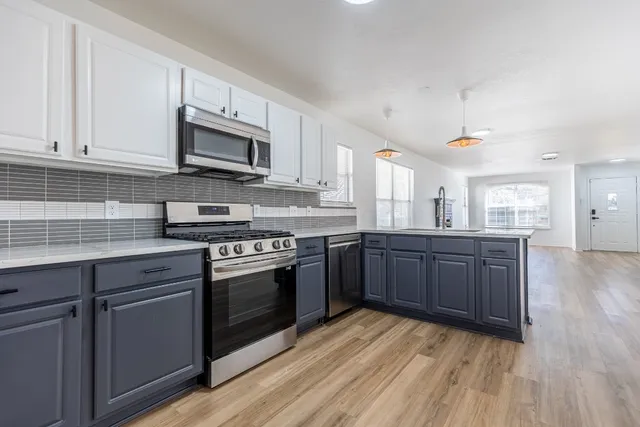 a kitchen with stainless steel appliances granite countertop a stove a sink and a microwave