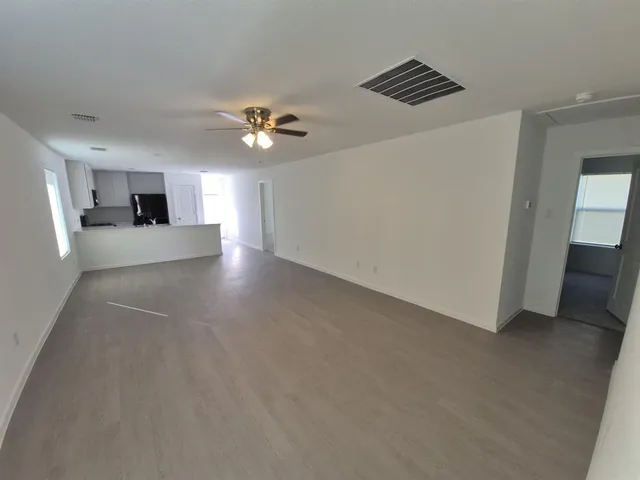 a view of an empty room with a ceiling fan window and a ceiling fan