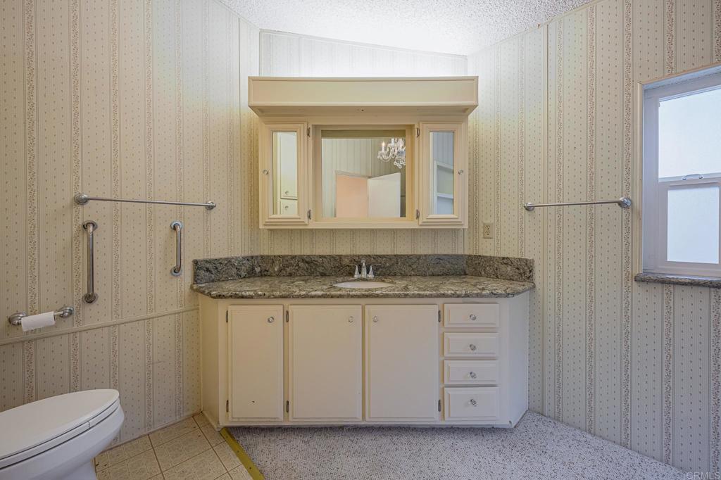 4650 Dulin Road, Unit 175 Fallbrook, CA 92003 - Photo 13 of 53 a bathroom with a granite countertop sink a toilet and a mirror