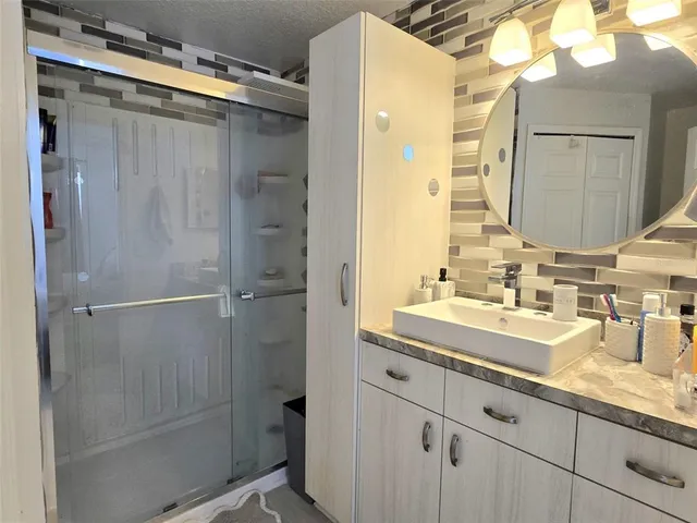 a bathroom with a shower sink vanity and mirror