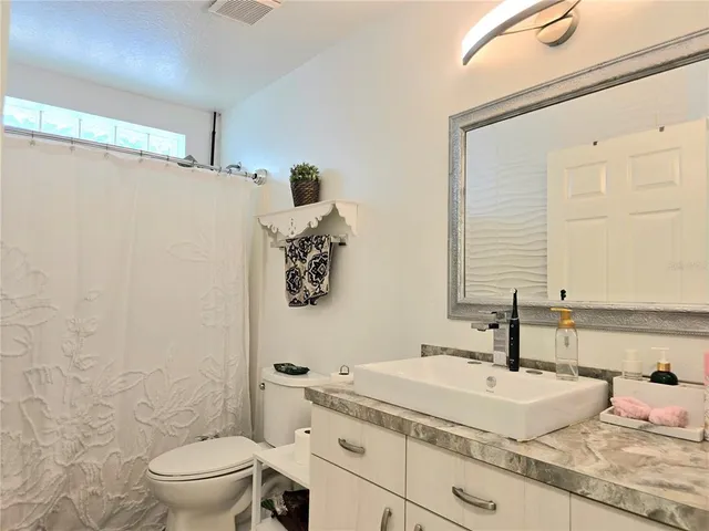 a bathroom with a granite countertop sink a toilet and a shower