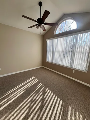 an empty room with wooden floor fan and windows