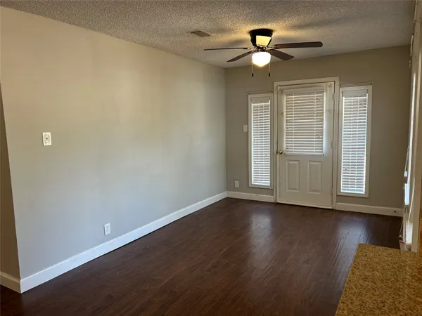 a view of an empty room with wooden floor and a window