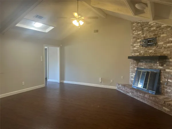a view of an empty room with chandelier fan and fire place
