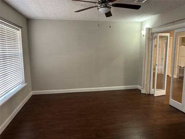 an empty room with wooden floor fan and windows