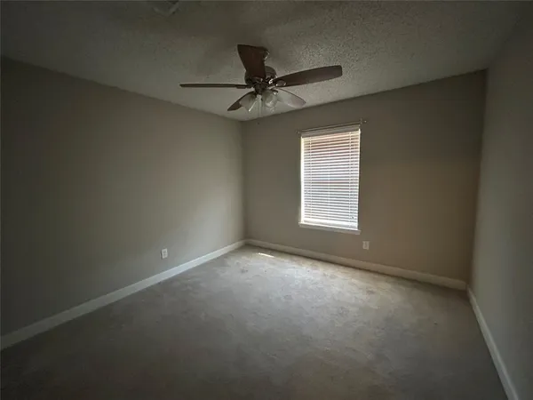 an empty room with a window and a fan
