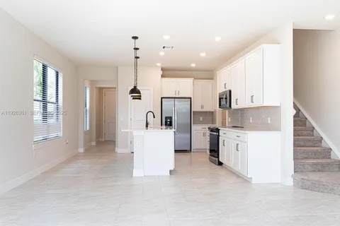 a kitchen with white cabinets and refrigerator