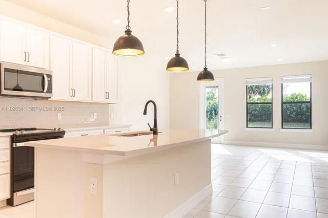 a kitchen with stainless steel appliances granite countertop a sink a microwave a stove and a granite counter tops