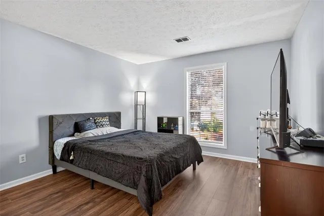 a bedroom with a bed a large window and wooden floor