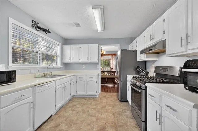 a kitchen with cabinets appliances a sink and a window