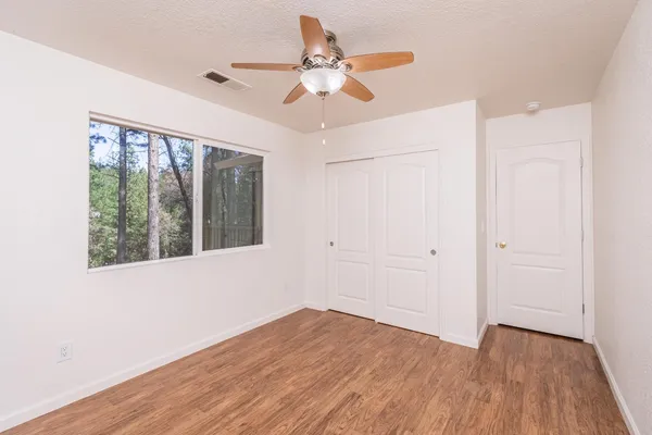 a view of an empty room with wooden floor and a window