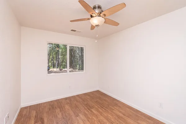 an empty room with a window and a fan