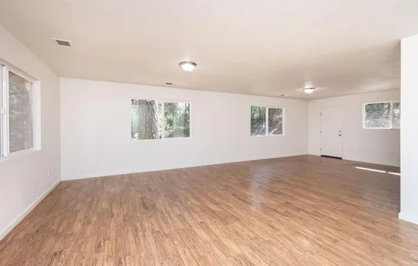 a view of empty room with wooden floor and fan