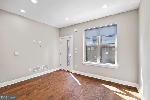 a view of an empty room with wooden floor and stairs