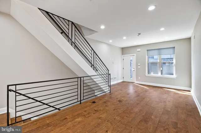 a view of an empty room with wooden floor and stairs