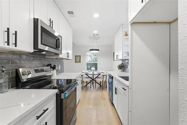 a kitchen with stainless steel appliances a stove a sink a microwave and a refrigerator