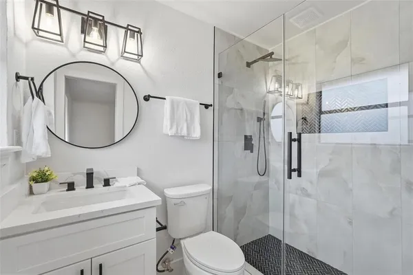a bathroom with a toilet a sink a mirror a vanity and shower